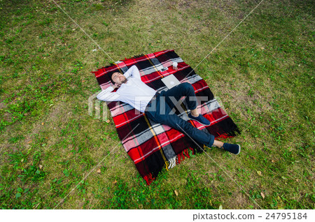 Happy young man with laptop relaxing on the grass 24795184