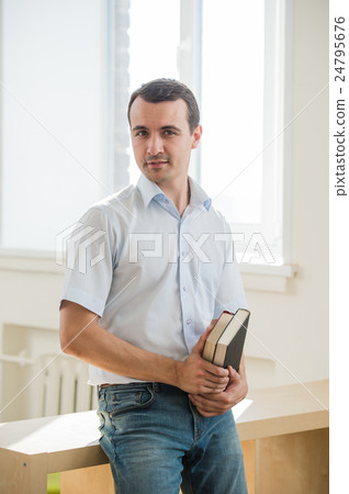 Portrait of young man holding books, looking at 24795676