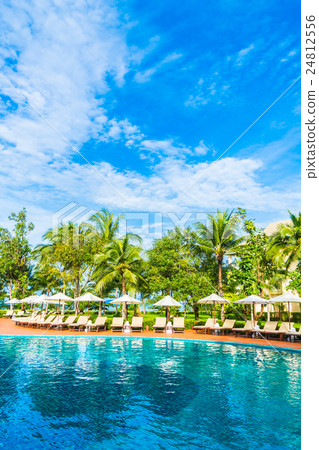 Umbrella and chair around swimming pool 24812556