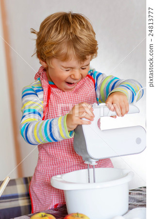 Funny blond kid boy baking apple cake indoors 24813777