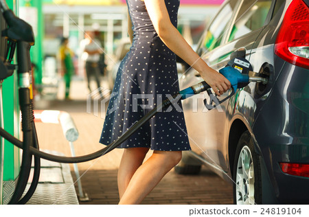 Woman fills petrol into her car 24819104