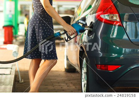 Woman fills petrol into her car 24819158