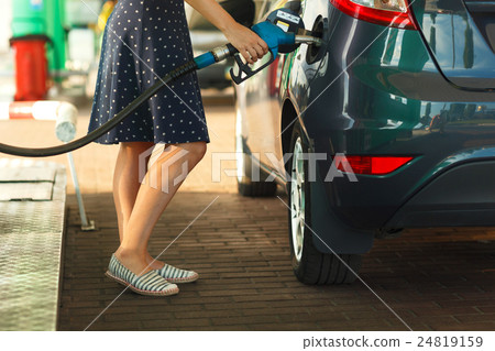 Woman fills petrol into her car 24819159