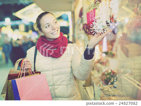 woman choosing Christmas decoration at market in evening time 24827082