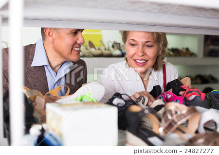 Mature couple picking shoes in boutique. 24827277