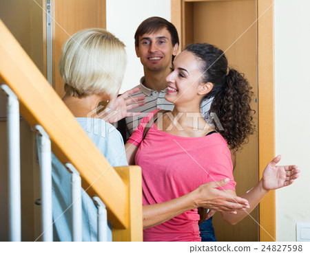 Cheerful senior woman greeting adult children coming with visit Cheerful senior woman greeting adult children coming with visit 24827598