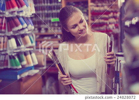 young woman selecting brushes in shop young woman selecting brushes in shop 24828072