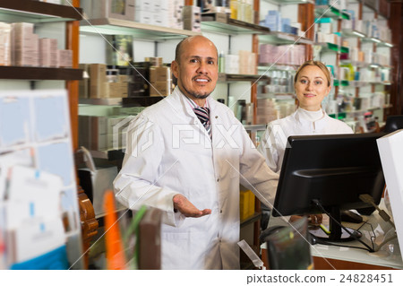 Two pharmacists standing next to shelves Two pharmacists standing next to shelves 24828451