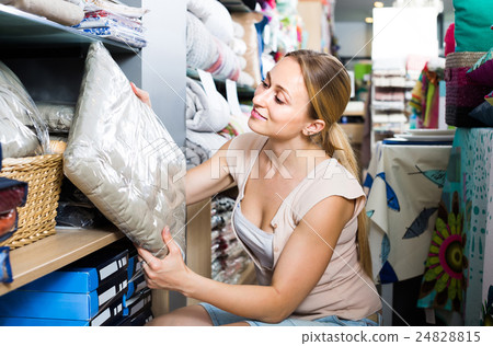 portrait of female customer choosing pillow in bedding section in shop 24828815