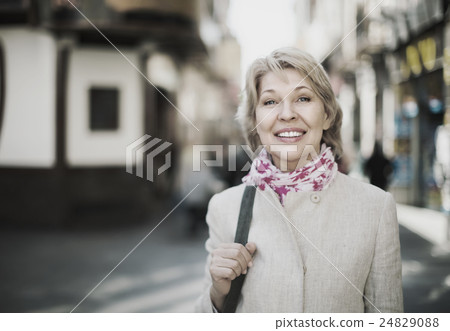 Senior woman standing on street in town. Senior woman standing on street in town. 24829088