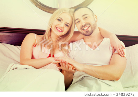 Cheerful young couple posing in family bed Cheerful young couple posing in family bed 24829272