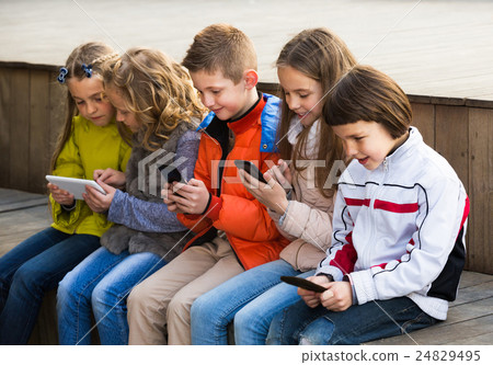 Friendly children sitting with mobile devices Friendly children sitting with mobile devices 24829495