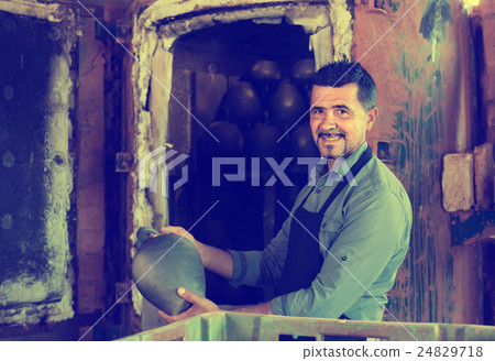 mature man potter holding black glazed ceramic vessel next to kiln mature man potter holding black glazed ceramic vessel next to kiln 24829718