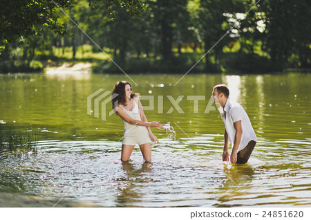 A guy and a girl spray water in the pond at the nature 6309. A guy and a girl spray water in the pond at the nature 6309. 24851620