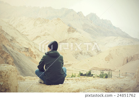 Young male traveler sitting on cliff, thinking  24851762