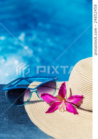 Sunglasses with flower and hat on swimming pool Sunglasses with flower and hat on swimming pool 24852459