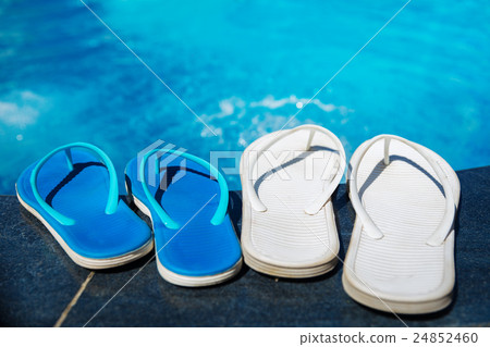 Beach slippers on border of swimming pool Beach slippers on border of swimming pool 24852460
