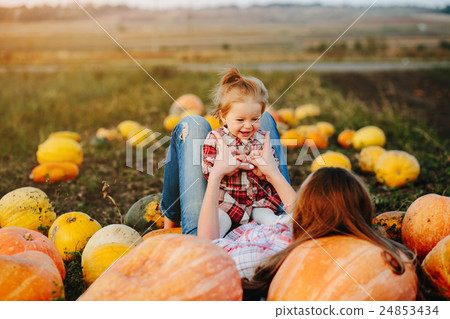 mother and daughter lie between pumpkins 24853434
