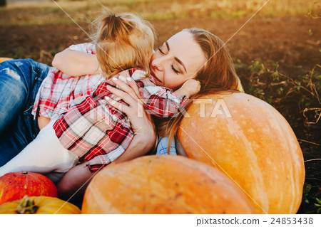 mother and daughter lie between pumpkins 24853438