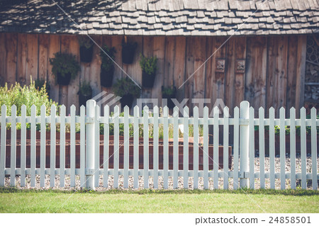 White picket fence in front af a wooden shed 24858501