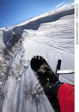 Snowboard over off-piste slope in sun day 24868010