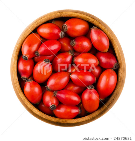 Red rose hips in a wooden bowl over white Red rose hips in a wooden bowl over white 24870681