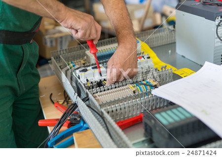Electrician assembling industrial electric cabinet Electrician assembling industrial electric cabinet 24871424