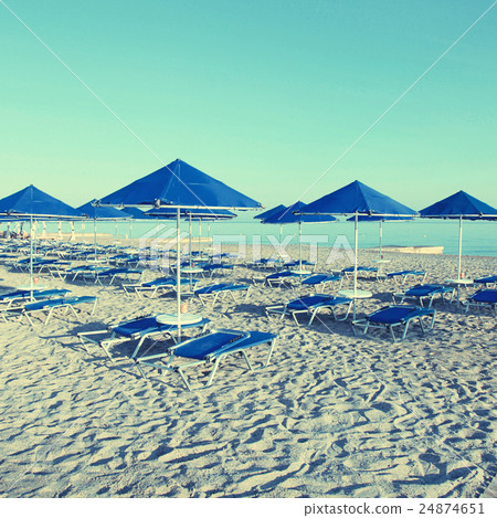 Blue umbrellas and chaise longue on sandy beach 24874651