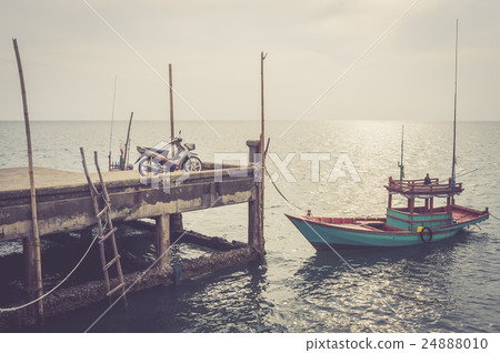 motorcycle and local fisher boat at pier. 24888010