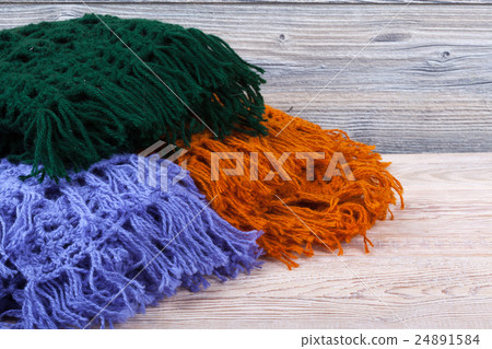Knitted woolen female shawls on wooden background Knitted woolen female shawls on wooden background 24891584