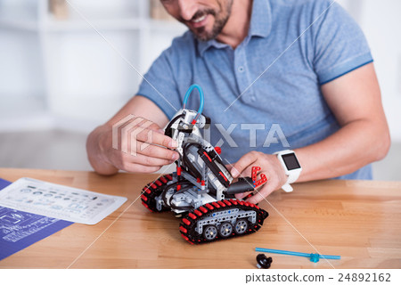 Male making cute small robot on the table Male making cute small robot on the table 24892162