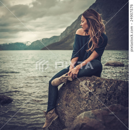 Beautiful woman posing on the shore of a wild lake 24907876