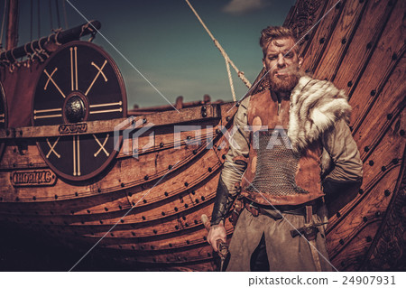 Viking warrior with axes standing near Drakkar on 24907931