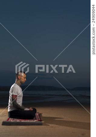 Tattoo Man meditating on the beach at sunset 24909044