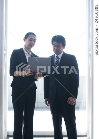 談話商人和的女商人，當觀看便攜式計算機在休息室時 24910885