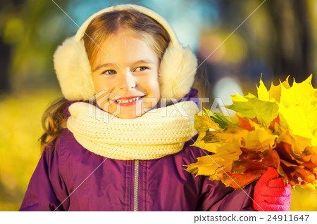 Happy little girl in earflaps with autumn leaves 24911647