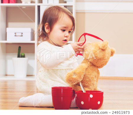 A girl playing with a stuffed bear A girl playing with a stuffed bear 24911973