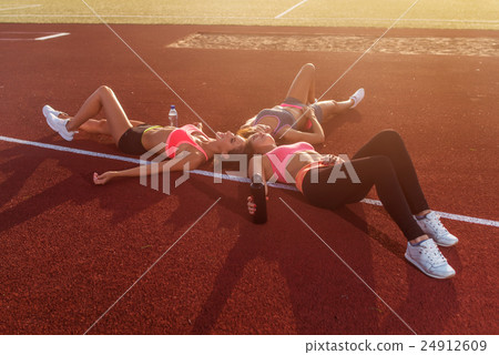 Group of tired fit girls lying on stadiun in Group of tired fit girls lying on stadiun in 24912609