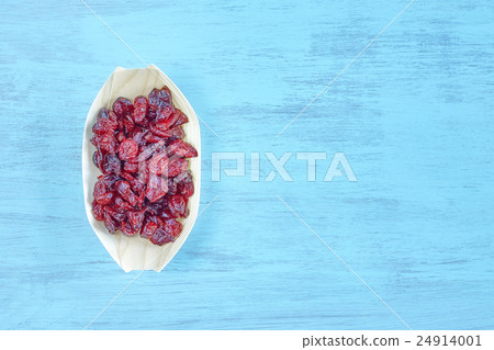 Dried cranberries in a wooden bowl on a table. 24914001
