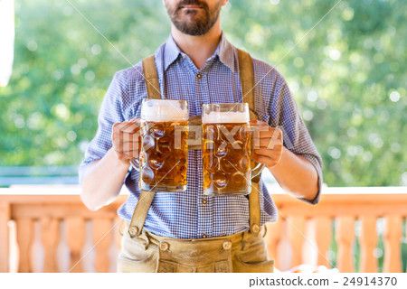 Man in traditional bavarian clothes holding mugs Man in traditional bavarian clothes holding mugs 24914370