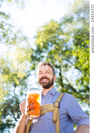 Man in traditional bavarian clothes holding mug of 24914372