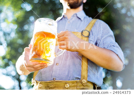 Man in traditional bavarian clothes holding mug of 24914373