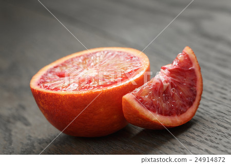 half and section of red orange on wooden table 24914872