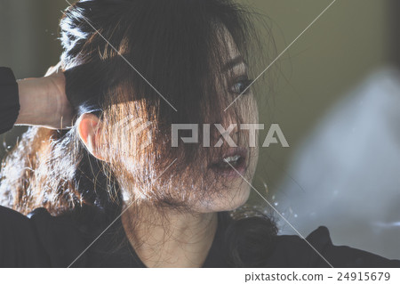 A woman looking at a mirror and making up makeup A woman looking at a mirror and making up makeup 24915679