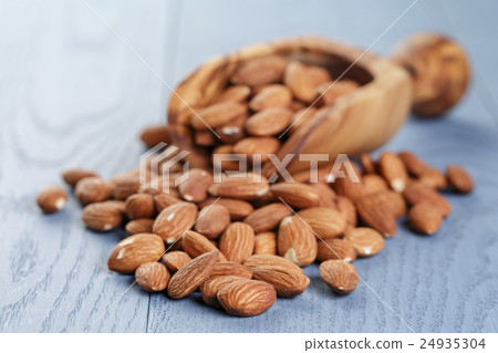 roasted almonds on blue wooden table with scoop 24935304