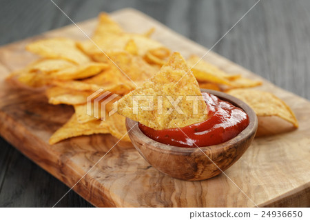 tortilla chips on olive board with tomato sauce 24936650