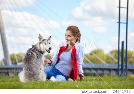 Woman playing with her dog on a city lawn Woman playing with her dog on a city lawn 24941723