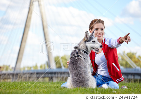 Woman playing with her dog on a city lawn Woman playing with her dog on a city lawn 24941724