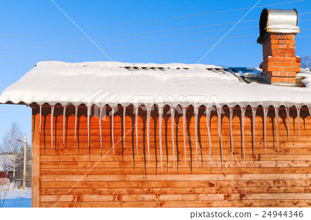 Long icicles on wooden wall in sunny winter day. 24944346