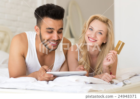 Young Couple Lying In Bed Using Tablet Computer 24948371